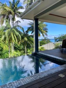 a house with a swimming pool and palm trees at Anse Soleil Beachcomber Hotel and Self Catering in Baie Lazare Mahé