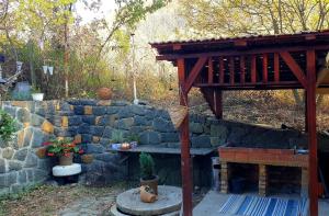 a garden with a stone wall and a wooden structure at Cabana Porolissum in Moigrad