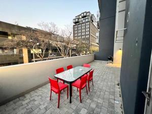 a patio with a table and red chairs on a building at Spacious Apartment in The Median Rosebank in Johannesburg