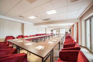 una sala de conferencias con mesas largas y sillas rojas en Hotel Lambert Medical Spa en Ustronie Morskie