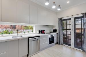 a kitchen with white cabinets and a large window at Modern Hamptons Cottage with Outdoor Deck in Mudgee