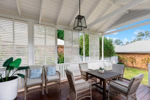 a screened porch with a wooden table and chairs at Modern Hamptons Cottage with Outdoor Deck in Mudgee
