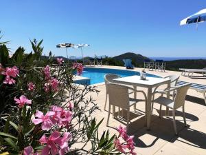 a patio with a table and chairs next to a pool at Saha tourist accommodation among olive trees and sea view in Sperlonga