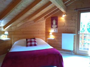 una camera con un letto in una cabina di legno di Le Chalet de Philippe a La Bresse