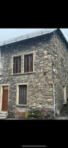 een stenen gebouw met drie ramen en een deur bij La croisée des chemins in Le Bourg-dʼOisans
