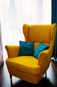 Una silla amarilla con dos almohadas azules. en House of colors, en Petroşani