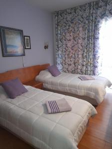 two beds in a hotel room with a window at Onisillos Hotel in Larnaka