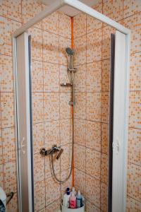 y baño con ducha y pared de azulejos de color naranja. en House of colors, en Petroşani