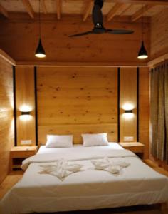 1 dormitorio con 1 cama blanca grande y paredes de madera en Nature fun resort en Pune