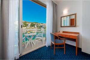 a room with a desk and a balcony with a table at Hotel Vis in Dubrovnik