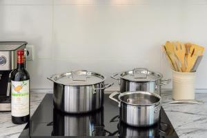 Drei Töpfe und Pfannen auf dem Herd, dazu eine Flasche Wein. in der Unterkunft Can Lovers in Sant Jordi