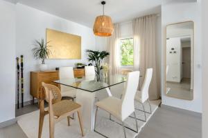 ein Esszimmer mit einem Glastisch und weißen Stühlen in der Unterkunft Can Lovers in Sant Jordi