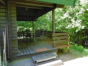een houten veranda van een hut met een tafel en stoelen bij Twistesee Ferienhaus 110 in Bad Arolsen