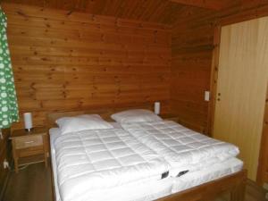 Twistesee Ferienhaus 110 في باد آرولزن: سرير في غرفة بجدار خشبي