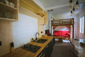 een keuken met een wastafel en een rode bank in een kamer bij Le chalet du bout du monde, en bord de rivière ! in Grez-sur-Loing