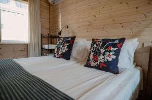ein Schlafzimmer mit einem Bett mit zwei Kissen darauf in der Unterkunft Ošupio Vasarnamis in Šventoji