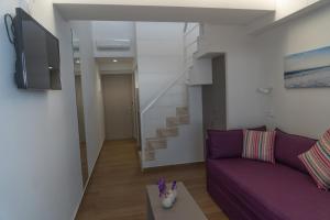 a living room with a purple couch and a staircase at Olympos Suites Apartments in Leptokaria