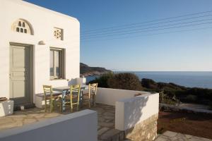 a white house with a table and chairs overlooking the ocean at Armira seaside house in Antiparos