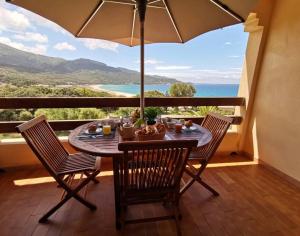d'une table et de chaises sur un balcon avec un parasol dans l'établissement F2, climatisé, vue mer, 100 m de la plage, à Casaglione