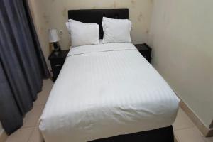 ein großes weißes Bett in einem Zimmer mit zwei Nachttischen in der Unterkunft SPOT ON 92196 Kost Axcel in Banjarmasin