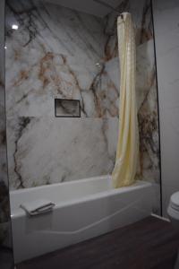 a marble bathroom with a shower curtain and a tub at Hyde Park Motel in Los Angeles