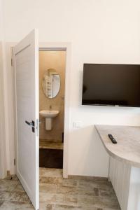 a bathroom with a sink and a television on a wall at Ošupio Vasarnamis in Šventoji