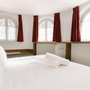 a bedroom with a large white bed with red curtains at Hotel Chalet Del Brenta in Madonna di Campiglio