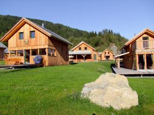 eine Gruppe von Holzgebäuden auf einem Feld mit einem Felsen in der Unterkunft Almdorf Stadl by ALPS RESORTS in Stadl an der Mur