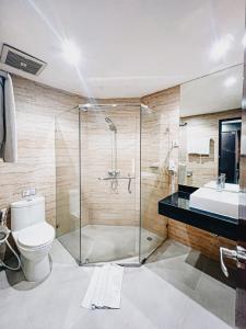 a bathroom with a shower and a toilet and a sink at Hermes Palace Hotel Medan in Medan