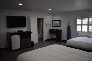 a bedroom with two beds and a flat screen tv at Hyde Park Motel in Los Angeles