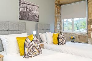 a bedroom with two beds with yellow and white pillows at Scalebar Bridge End Mill in Settle