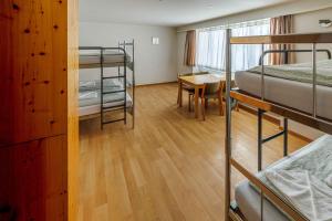 エンゲルベルクにあるEngelberg Youth Hostelの二段ベッド、テーブル、デスクが備わるドミトリールームです。