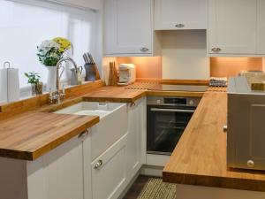 una cocina con armarios blancos y fregadero en Beachview Cottage Scratby en Scratby