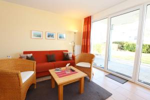 ein Wohnzimmer mit einem roten Sofa und einem Tisch in der Unterkunft Haus Möwe II - Ferienwohnung 01 mit Terrasse in Ostseebad Sellin