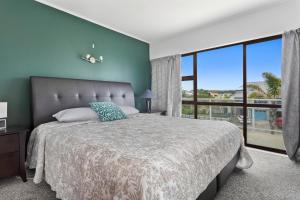 una camera da letto con un letto grande e una grande finestra di Treasure on Tawai - Ohope Holiday Home a Ohope Beach