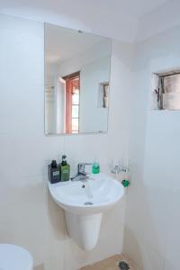 a white bathroom with a sink and a mirror at Hanoi Retro 80S Homestay in Hanoi