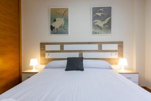 - une chambre avec un grand lit blanc et deux lampes dans l'établissement Apartagal-Ed Batel Foz, à Foz
