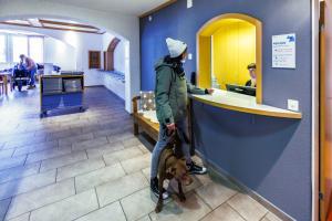 una persona con un perro parado en un mostrador en Engelberg Youth Hostel, en Engelberg