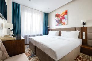 una habitación de hotel con una cama grande y una silla en Grand Mildom Hotel en Almaty