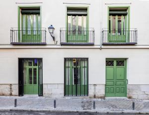a row of green doors on a white building at Calatrava - Darya Living in Madrid