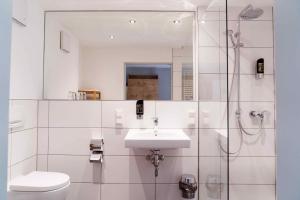 a white bathroom with a sink and a toilet at Schroeders Wein-Style-Hotel in Trier