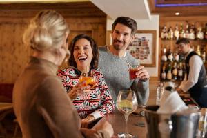 un gruppo di persone seduti intorno a un bar con bevande di Rasmushof - Hotel Kitzbühel a Kitzbühel