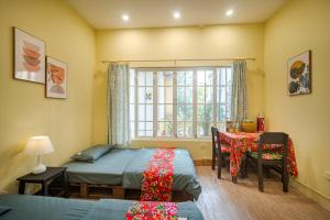 a bedroom with two beds and a table and a window at Hanoi Retro 80S Homestay in Hanoi