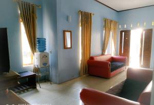 Homestay Putra Sindang Asih Batukaras في Batukaras: غرفة معيشة مع كرسي احمر واريكة