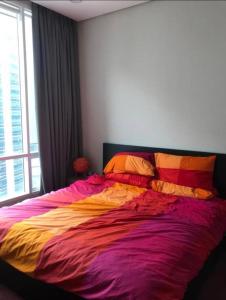 um quarto com uma cama grande e lençóis coloridos em Soho Suites KLCC by Harry em Kuala Lumpur