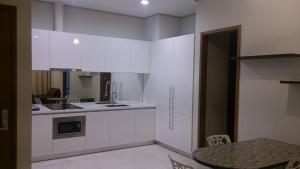 uma cozinha com armários brancos e uma mesa em Soho Suites KLCC by Harry em Kuala Lumpur