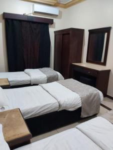 Habitación de hotel con 3 camas y espejo en Basma Plaza en Abha