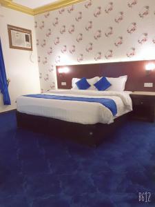 1 dormitorio con 1 cama grande con alfombra azul en Basma Plaza, en Abha