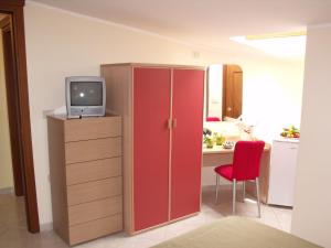 a room with a tv and a desk with a red cabinet at Albergo Ristorante Grace in Vibo Valentia