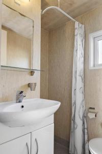 a bathroom with a white sink and a shower at First Camp Råbjerg Mile - Skagen in Skagen